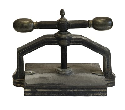 Lot 557 - Bookpress. A cast iron bookpress, finished in black, with brass handle ends & finial