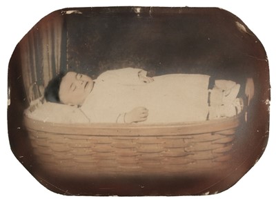 Lot 24 - Post-mortem of a child. A full-length portrait of a young child lying in a wicker basket, c. 1880s