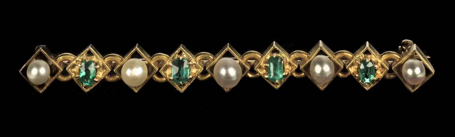 Lot 69 - Brooch. Edwardian gold bar brooch set with emeralds and pearls