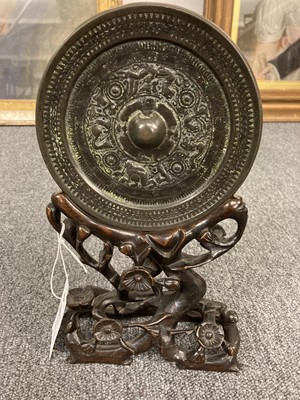 Lot 159 - Chinese. An archaic bronze mirror on a hardwood stand