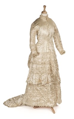 Lot 548 - Dress. A cream satin wedding gown with bustled trained skirt, circa 1880s