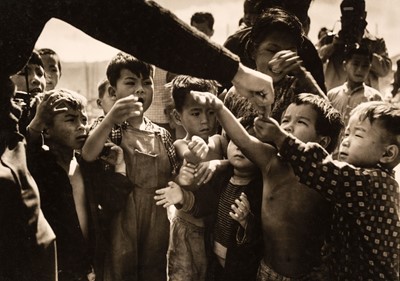 Lot 55 - Hong Kong. A group of children getting candy, by K. C. Chew, 1961, vintage gelatin silver print