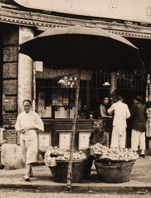 Lot 66 - Hoppé (Emil Otto, 1878-1972). A woman selling oranges outside a money changer's shop, c. 1930s